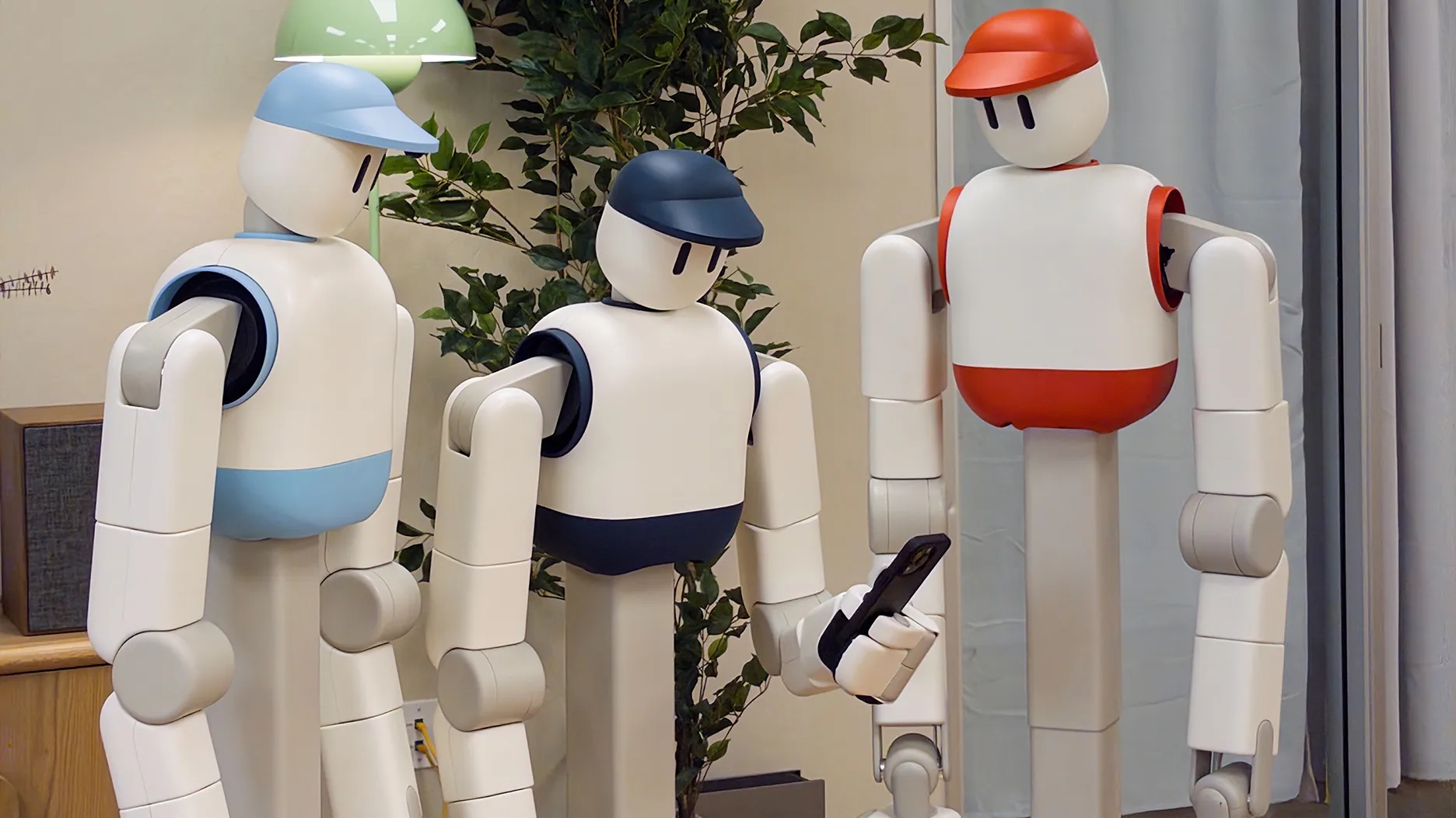 Memo, the Sunday Robotics household robot: white wheeled body, two articulated arms, a cartoon face with long button-like eyes, wearing a colourful baseball cap